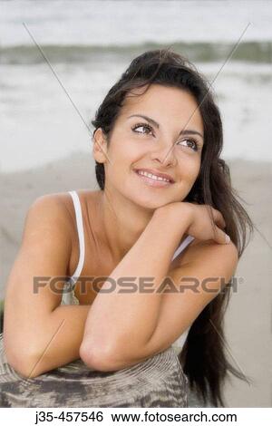 A smiling young girl 20's to 30's with long dark hair, leans her arms on a pier post during a breezy summers day View Large Photo Image Stock Photograph - A smiling young girl 20's to 30's with long dark hair, leans her arms on a pier post during a breezy summers day. Fotosearch