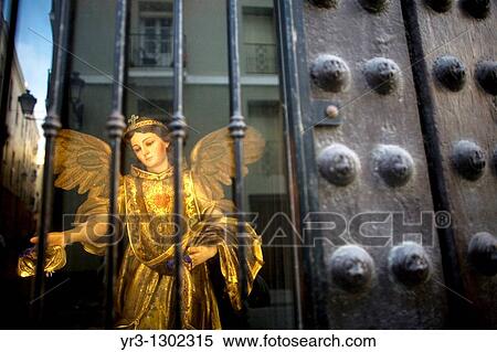 Stock Photography - A statue of Saint Raphael Arcangel sits behind a window as the city of Cadiz is reflected in Andalusia, Spain, April 17, 2010. Fotosearch