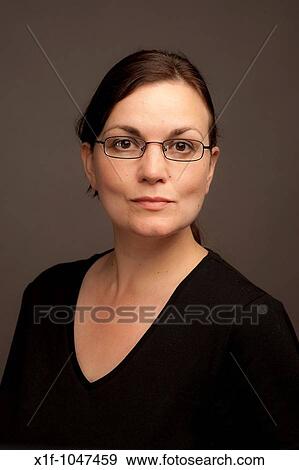 Stock Photo - a stern severe looking 30 year old brunette woman with brown eyes wearing glassses. Fotosearch