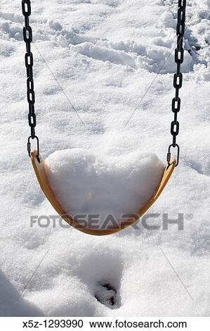 Stock Image - A swing full of snow in the Winter. Fotosearch