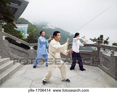 Picture - A Tai Chi Master and his student practice martial arts at The Peak with The Peak Tower in background. Fotosearch