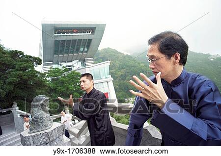 Stock Photo - A Tai Chi Master and his student practice martial arts at The Peak with The Peak Tower in background. Fotosearch