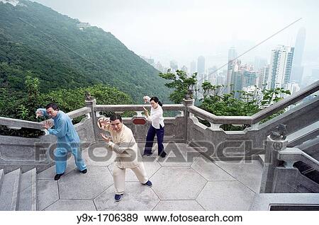Stock Photo - A Tai Chi Master and his student practice martial arts at The Peak with The Peak Tower in background. Fotosearch