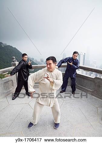 Stock Photo - A Tai Chi Master and his student practice martial arts at The Peak with The Peak Tower in background. Fotosearch