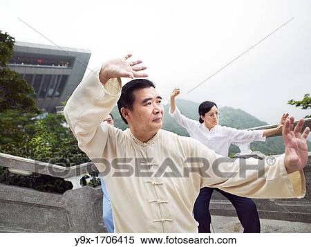Stock Photography - A Tai Chi Master and his student practice martial arts at The Peak with The Peak Tower in background. Fotosearch