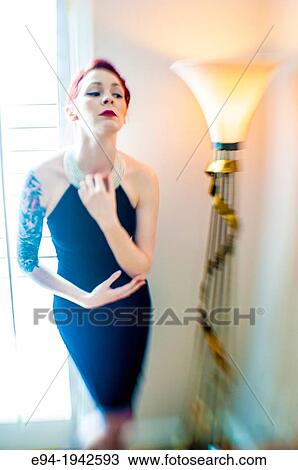 A tattooed 24 year old red headed woman wearing a small black dress indoors. View Large Photo Image Stock Image - A tattooed 24 year old red headed woman wearing a small black dress indoors.. Fotosearch