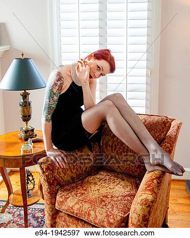 A tattooed 24 year old red headed woman wearing a small black dress indoors. View Large Photo Image Stock Photo - A tattooed 24 year old red headed woman wearing a small black dress indoors.. Fotosearch