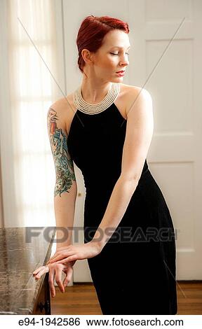 A tattooed 24 year old red headed woman wearing a small black dress indoors. View Large Photo Image Stock Photograph - A tattooed 24 year old red headed woman wearing a small black dress indoors.. Fotosearch