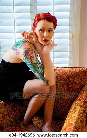 A tattooed 24 year old red headed woman wearing a small black dress indoors. View Large Photo Image Stock Photography - A tattooed 24 year old red headed woman wearing a small black dress indoors.. Fotosearch