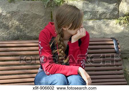 Stock Image - A teen girl contemplates many important teen issues and ideas as she rests for a few minutes while waiting for friends. Fotosearch
