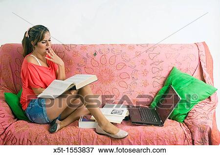 A teen studies on a couch in her room View Large Photo Image Stock Photo - A teen studies on a couch in her room. Fotosearch