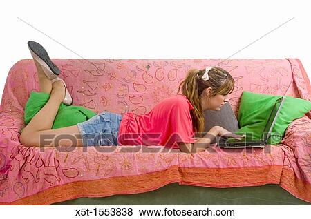A teen studies on a couch in her room with a laptop View Large Photo Image Stock Photo - A teen studies on a couch in her room with a laptop. Fotosearch
