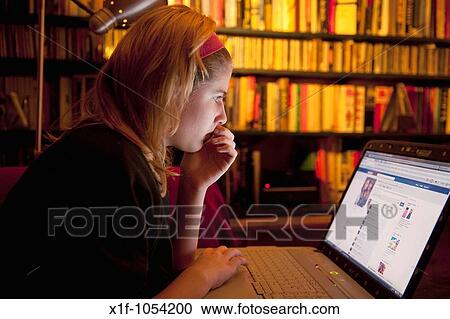 Stock Image - A teenage girl reading her Facebook page on a laptop computer at home, UK. Fotosearch