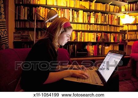 Stock Photo - A teenage girl reading her Facebook page on a laptop computer at home, UK. Fotosearch