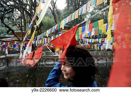 Stock Image - A teenage girl with a Hindu tilaka marking walks under prayer flags at Tiger Hill.. Fotosearch
