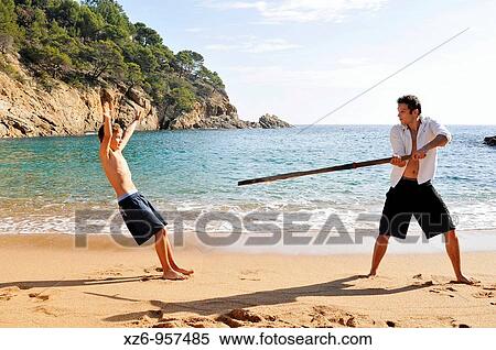 Stock Photography - A teenager playing with his older brother at the beach. Fotosearch