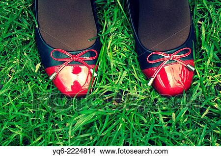 Picture - A teenager's legs in red and black shoes on the grass.. Fotosearch