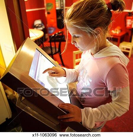 Stock Photograph - A ten year old girl child using a touch screen panel computer information display in Ceredigion Museum, Aberystwyth Wales UK. Fotosearch
