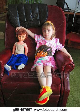 A three year girl with a dolly sits in her grandfather's chair during a visit. View Large Photo Image Stock Photo - A three year girl with a dolly sits in her grandfather's chair during a visit.. Fotosearch
