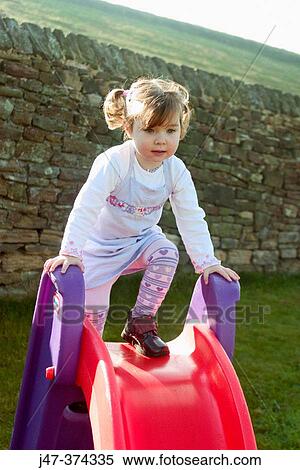 Stock Photography - A three year old girl playing on a slide. Fotosearch