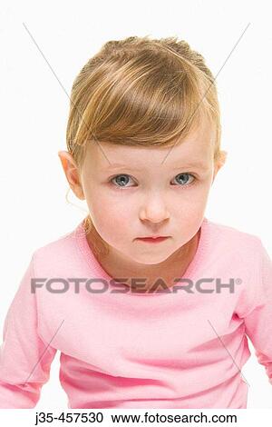 Stock Image - A three year old girl with blonde hair wearing a pink top and hair pulled back, looks into camera.. Fotosearch