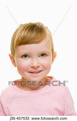 Stock Image - A three year old girl with blonde hair wearing a pink top and hair pulled back, looks into camera with a happy expression.. Fotosearch