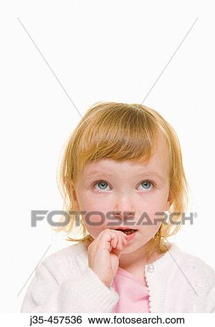 A three year old girl with blonde hair wearing a white sweater and a pink top looks upwards with a concerned expression while biting on her fingers. View Large Photo Image Stock Photograph - A three year old girl with blonde hair wearing a white sweater and a pink top looks upwards with a concerned expression while biting on her fingers.. Fotosearch