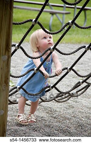 Stock Image - A toddler at the park, climbing a rope net.. Fotosearch