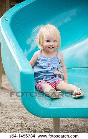 A toddler at the park, smiling on a slide. View Large Photo Image Picture - A toddler at the park, smiling on a slide.. Fotosearch