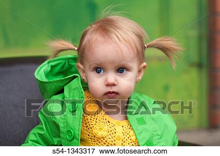 Stock Photo - A toddler outdoors in a bright green raincoat. Fotosearch