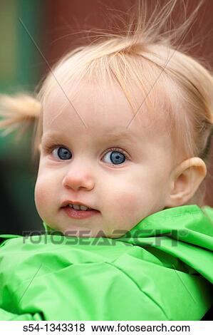 Stock Photo - A toddler outdoors in a bright green raincoat. Fotosearch