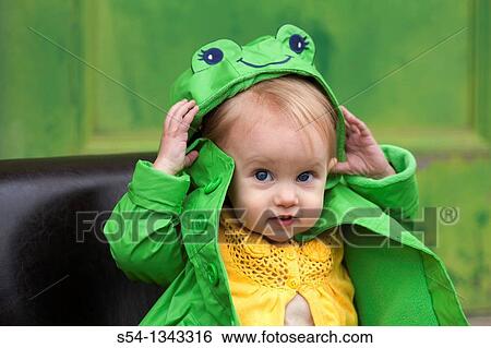 Stock Photograph - A toddler outdoors in a bright green raincoat. Fotosearch