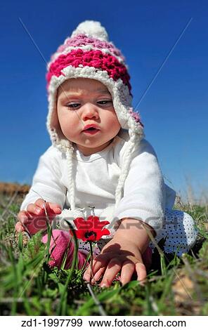 A toddler sits in a green field and play with flowers. View Large Photo Image Stock Photo - A toddler sits in a green field and play with flowers.. Fotosearch