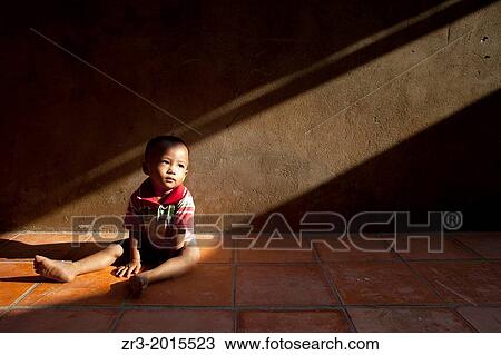 A toddler sits in a shaft of light in a village outside of Phnom Penh, Cambodia. View Large Photo Image Stock Image - A toddler sits in a shaft of light in a village outside of Phnom Penh, Cambodia.. Fotosearch
