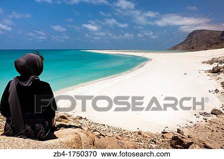 A tourist sitting on a top rock viewing the sand bar on the seaward edge of Ditwah lagoon near Qalansiyah, Socotra island, listed as World Heritage by UNESCO, Yemen, Arabia, West Asia. View Large Photo Image Stock Image - A tourist sitting on a top rock viewing the sand bar on the seaward edge of Ditwah lagoon near Qalansiyah, Socotra island, listed as World Heritage by UNESCO, Yemen, Arabia, West Asia.. Fotosearch
