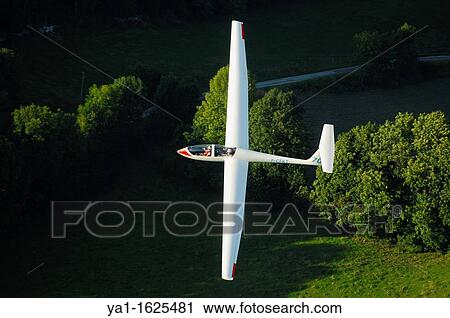 A trainer glider Grob Twin Astir fliying over Alps forest in the evening light, Challes les Eaux, Savoie, France View Large Photo Image Stock Image - A trainer glider Grob Twin Astir fliying over Alps forest in the evening light, Challes les Eaux, Savoie, France. Fotosearch