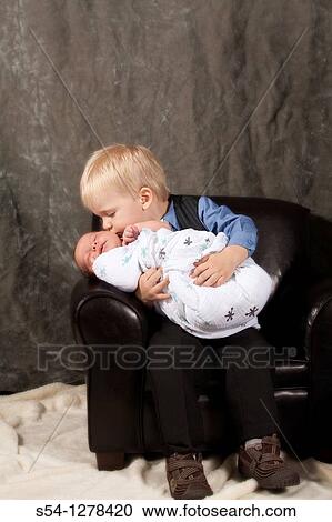 A two year old boy kisses his newborn baby brother View Large Photo Image Stock Image - A two year old boy kisses his newborn baby brother. Fotosearch