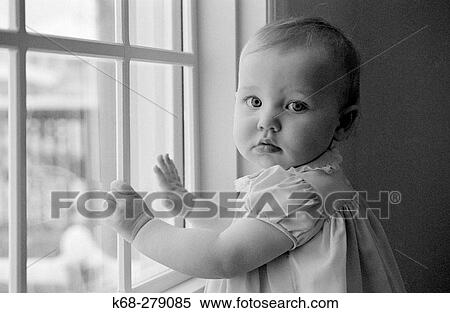 a two year old girl stands by a window View Large Photo Image Stock Photography - a two year old girl stands by a window. Fotosearch