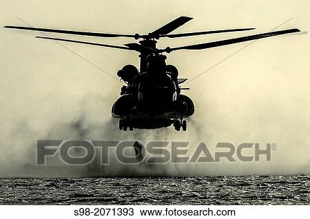 Stock Image - A U. S. Air Force airman from the 23rd Special Tactics Squadron jumps out of the back of a MH-47 Chinook helicopter at Wynnehaven Beach, Fla., April 9, 2013.. Fotosearch