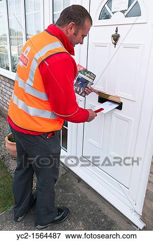 A uk Royal Mail Postman delivers a letter using the new tool to stop dogs biting their fingers View Large Photo Image Stock Photo - A uk Royal Mail Postman delivers a letter using the new tool to stop dogs biting their fingers. Fotosearch