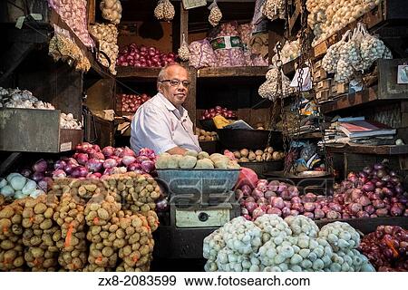 A vegetable vendor sits in his shop in a wholesale produce market. View Large Photo Image Stock Photo - A vegetable vendor sits in his shop in a wholesale produce market.. Fotosearch