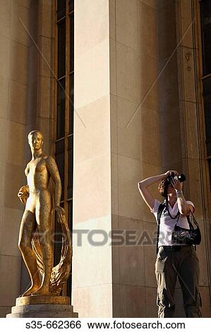 A visitor taking photo beisde a gilded bronze statue in the central square of the Palais de Chaillot. Paris. France View Large Photo Image Stock Photograph - A visitor taking photo beisde a gilded bronze statue in the central square of the Palais de Chaillot. Paris. France. Fotosearch