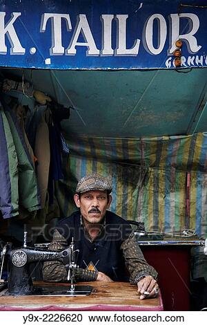 A well dressed tailor with a cigarette in front of his sewing machine. View Large Photo Image Stock Image - A well dressed tailor with a cigarette in front of his sewing machine.. Fotosearch