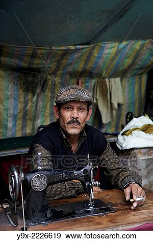 A well dressed tailor with a cigarette in front of his sewing machine. View Large Photo Image Stock Photo - A well dressed tailor with a cigarette in front of his sewing machine.. Fotosearch