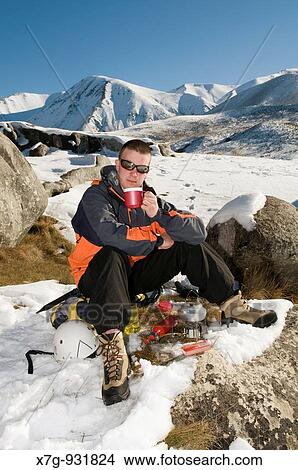 Picture - A winter hiker relaxes with a hot drink, Canterbury high country, New Zealand. Fotosearch