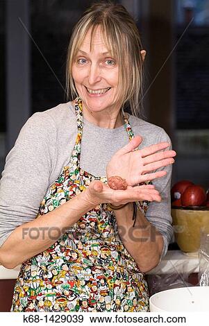 Stock Photo - a woman, 56, prepares meat ball in her kitchen. Fotosearch