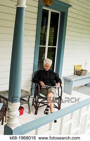 Stock Photograph - A woman, 66, relaxing on the porch of the Breezy Bay Bed and Breakfast on Saturna Island, Gulf Islands, BC, Canada.. Fotosearch