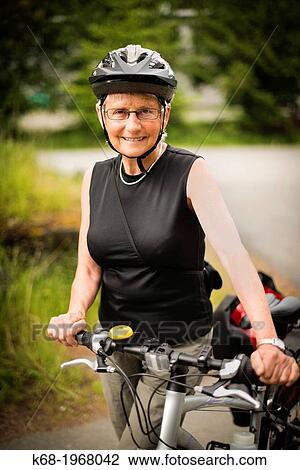 Stock Image - A woman, 66, with her bicycle on Saturna Island, Gulf Islands, British Columbia, Canada. Fotosearch