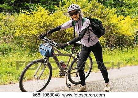 a woman, 75, pushes her bicycle on a road on Saturna Island, Gulf Islands, British Columbia, Canada View Large Photo Image Stock Photo - a woman, 75, pushes her bicycle on a road on Saturna Island, Gulf Islands, British Columbia, Canada. Fotosearch