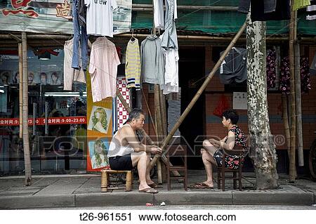 A woman and a man sitting outside his home with his clothes on the street. Shanghai, China View Large Photo Image Stock Image - A woman and a man sitting outside his home with his clothes on the street. Shanghai, China. Fotosearch